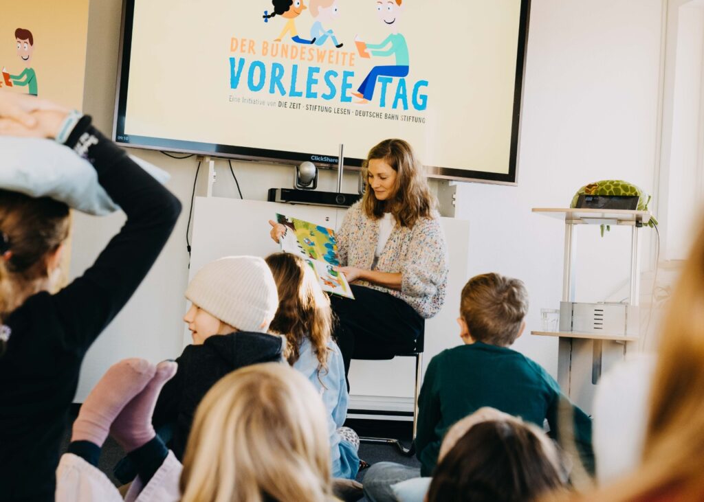 eine Frau liest Kindern aus einem Buch vor