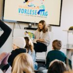 eine Frau liest Kindern aus einem Buch vor