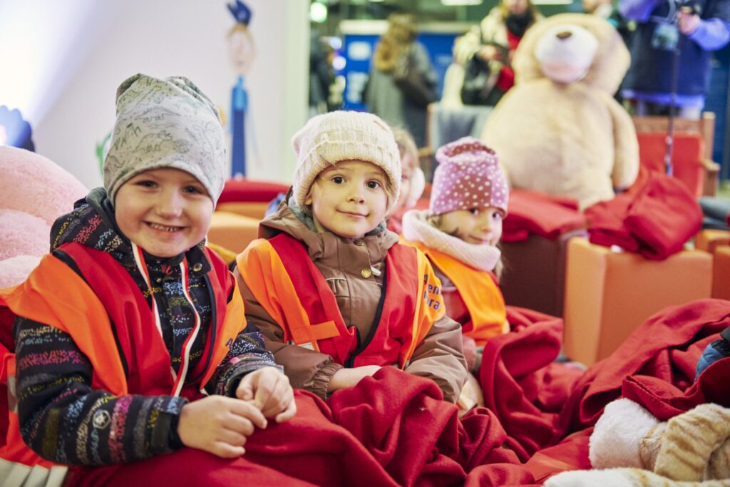 Drei Kinder schauen lachend in die Kamera