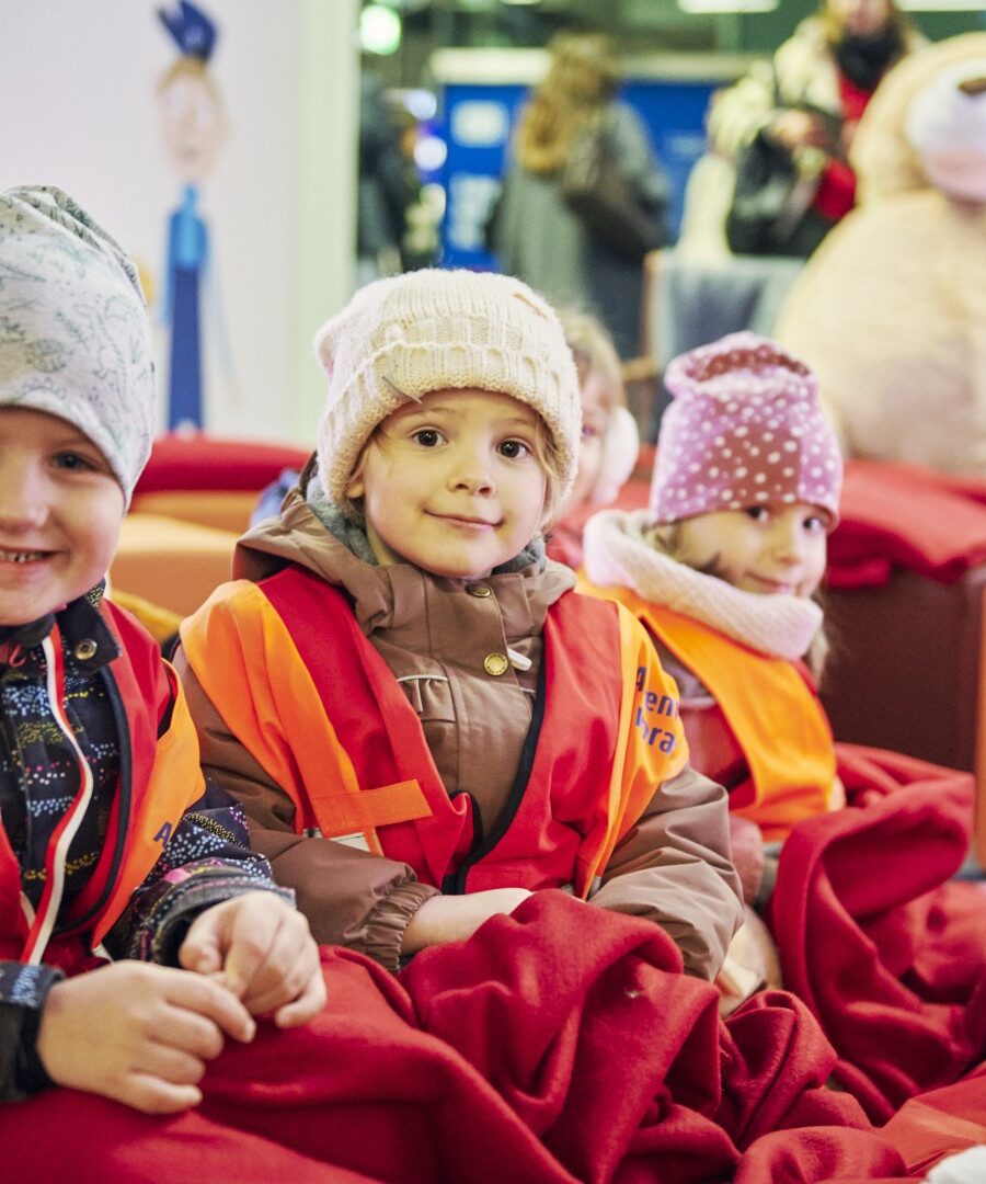 Drei Kinder schauen lachend in die Kamera
