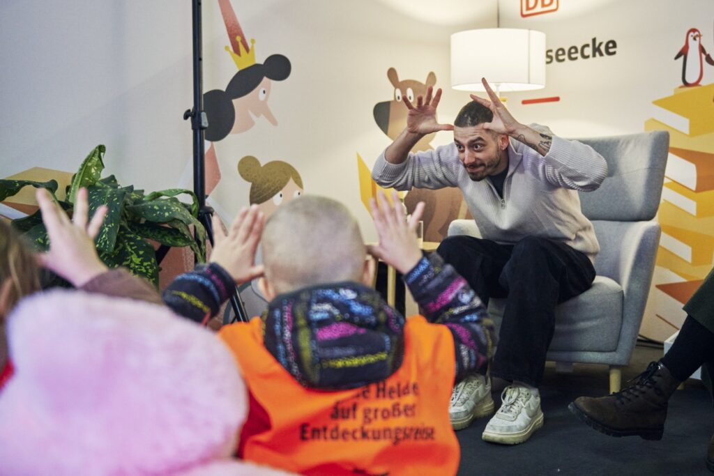 ein Mann liest in Gebärdensprache eine Gruppe von Kindern vor