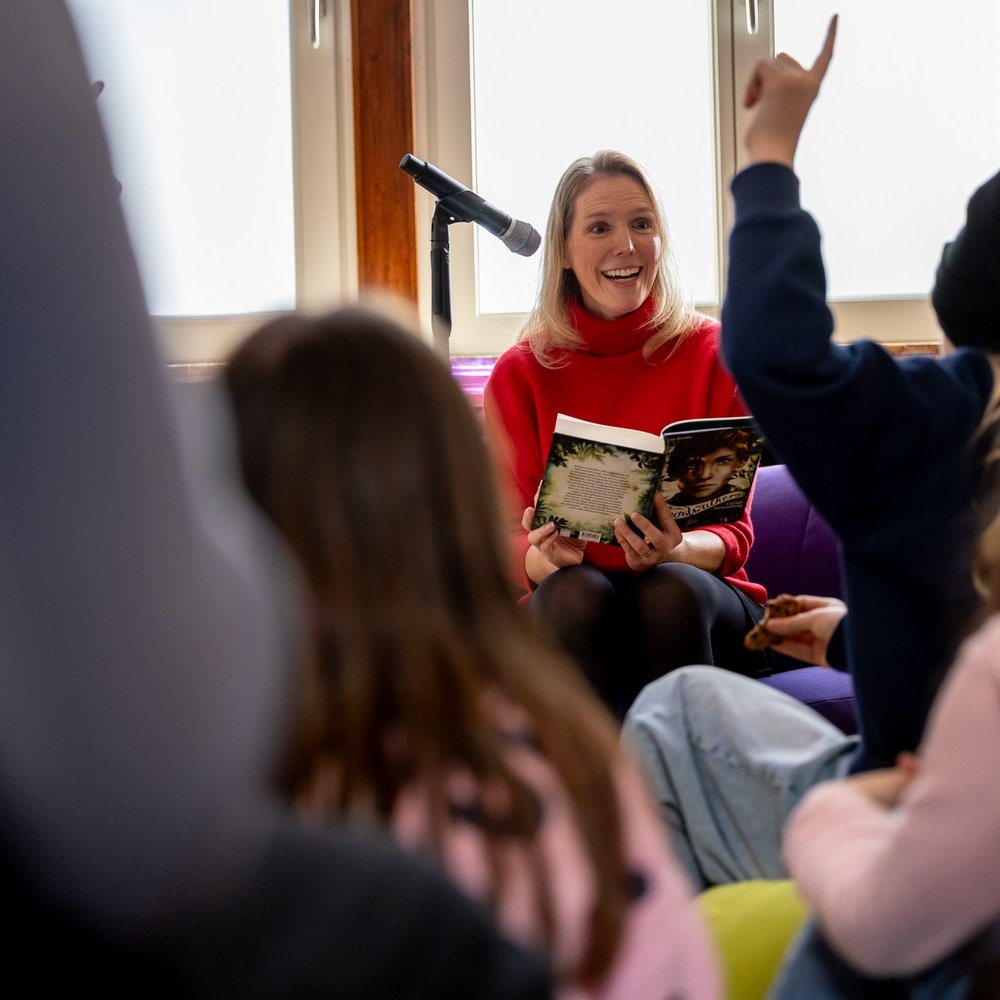 Lesebotschafterin Maja Sommer sitzt vor einer Gruppe Kindern und liest vor