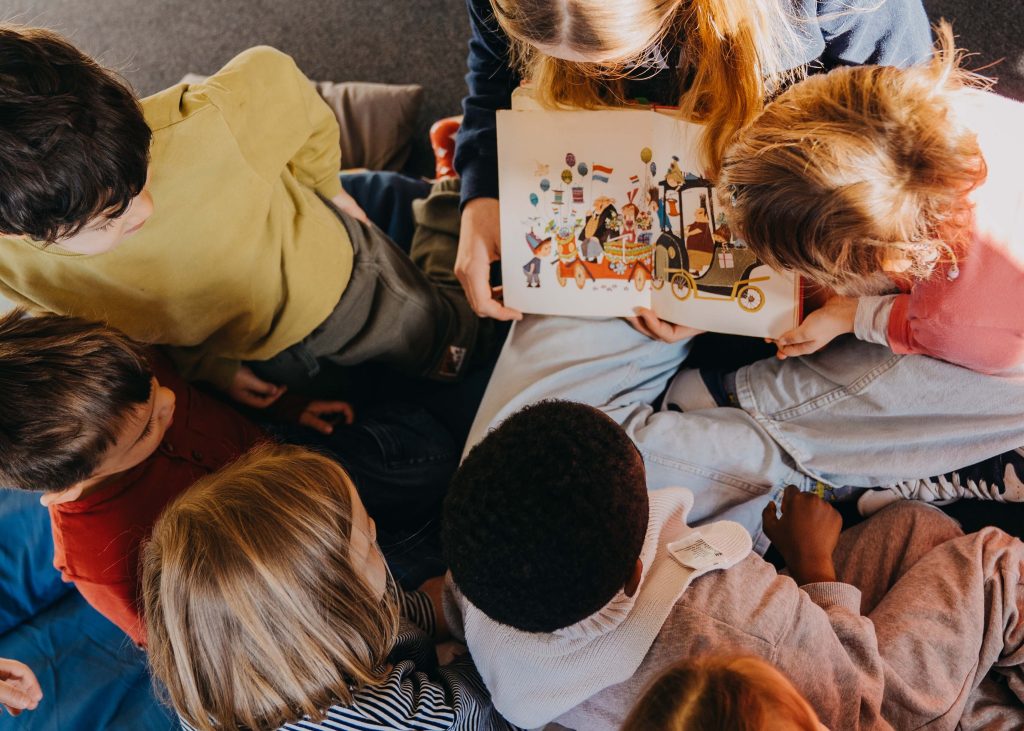 eine Frau liest Kinder aus einem Buch vor